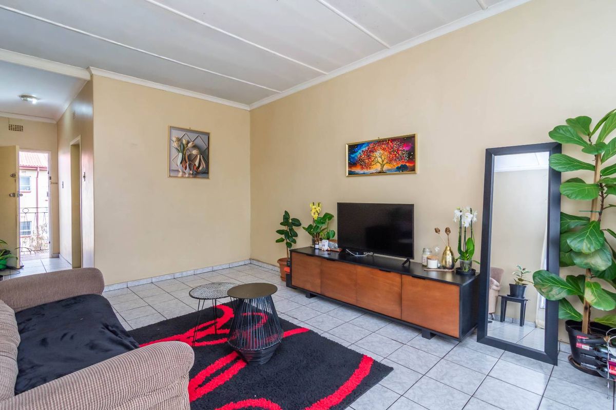 A living room featuring tiled flooring and a panelled ceiling, providing a functional and neutral space for relaxation.