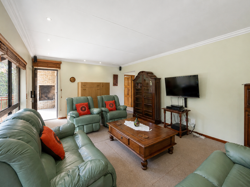 A spacious living room featuring neutral walls, carpet flooring, recessed lighting, and large sliding glass doors providing access to an outdoor patio area.