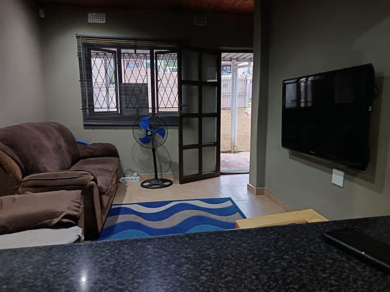 A living room featuring tiled flooring, a timber ceiling, and direct access to an outdoor area through a security-fitted door.