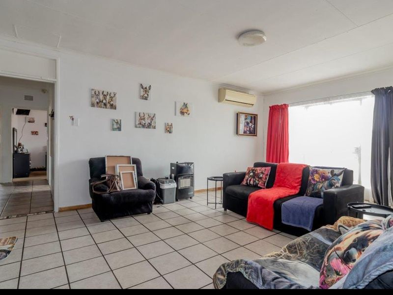 A living room featuring tiled flooring and a wall-mounted air conditioning unit, providing a functional and open space for relaxation.