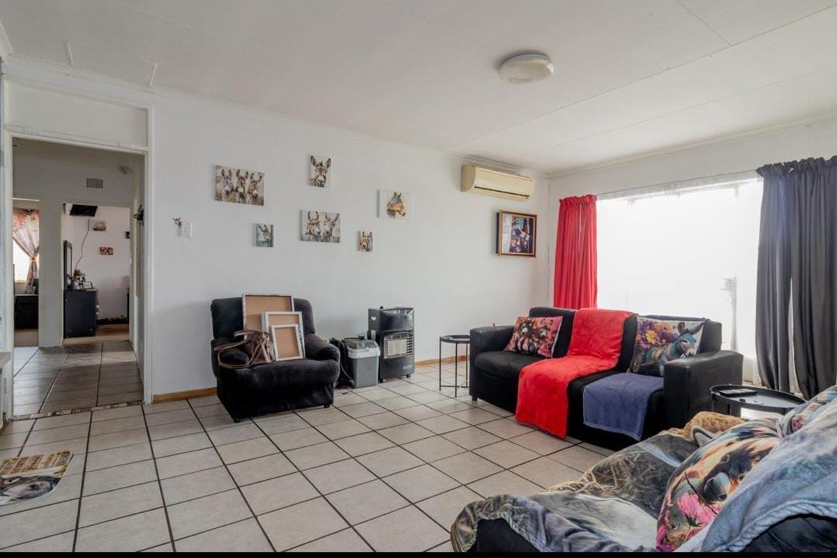 A living room featuring tiled flooring and a wall-mounted air conditioning unit, providing a functional and open space for relaxation.