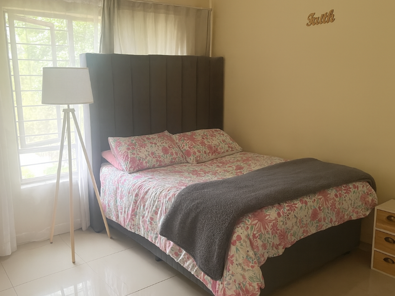 A bedroom featuring tiled flooring and a large window with security bars, providing natural light.