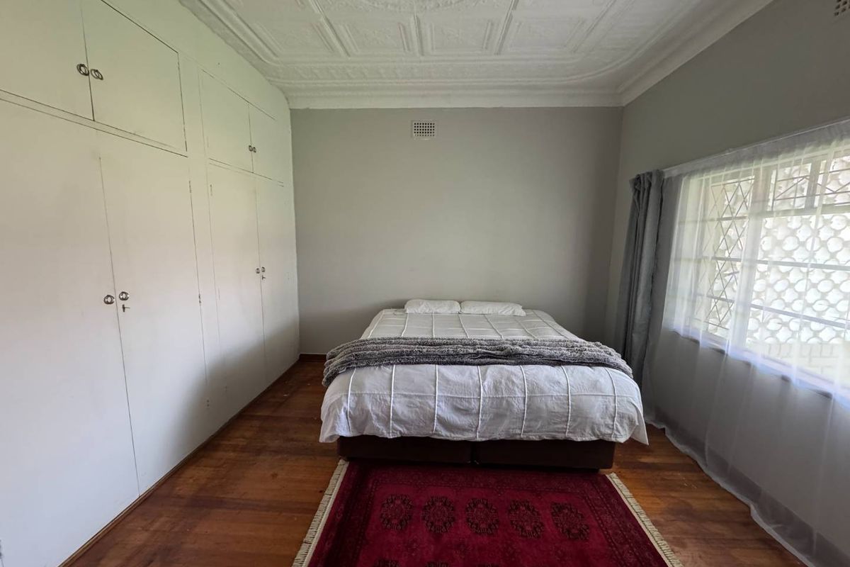 A bedroom featuring original pressed metal ceilings, polished timber flooring, and extensive built-in floor-to-ceiling cabinetry.