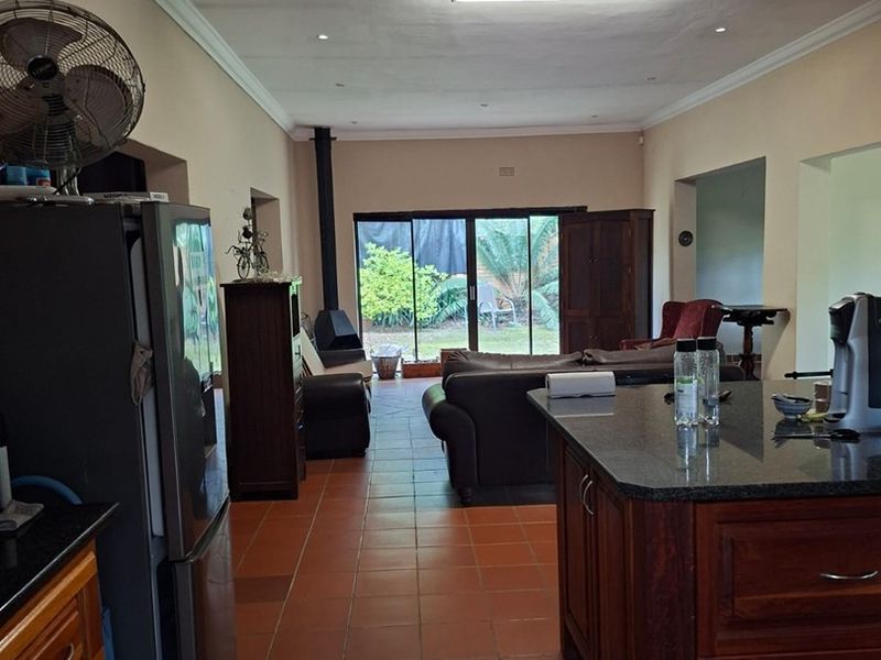 Spacious open-plan kitchen and living area featuring terracotta tiling, a granite-topped island, and a freestanding fireplace with access to the rear garden.