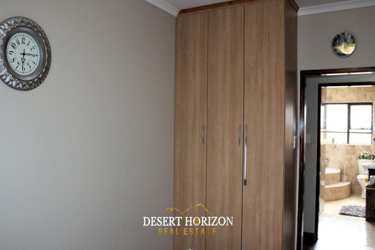 Bedroom featuring a full-height built-in wooden wardrobe with a doorway leading to an adjoining bathroom.