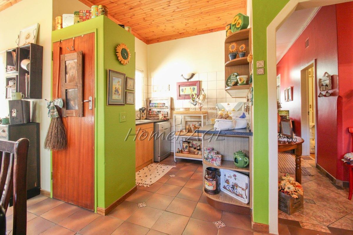 A compact kitchen area featuring wooden ceiling paneling, tiled flooring, and built-in cabinetry with a functional layout.