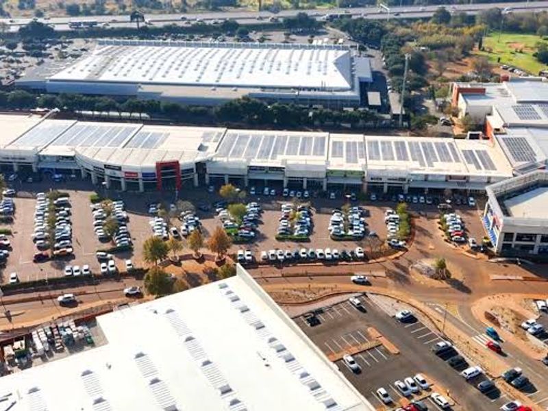 Aerial view of a large commercial office and retail complex featuring extensive parking facilities and rooftop solar panel installations.