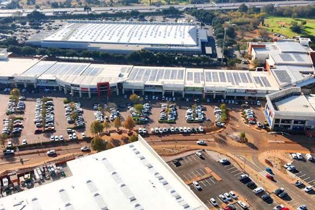 Aerial view of a large commercial office and retail complex featuring extensive parking facilities and rooftop solar panel installations.