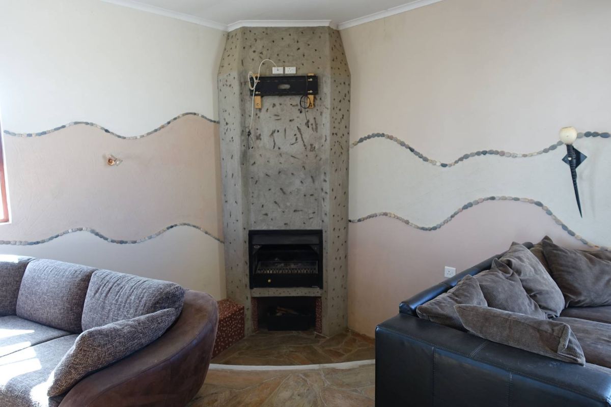 Living room featuring a unique corner fireplace with a concrete surround and decorative stone wall accents.