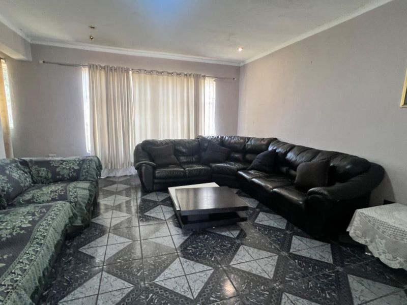 Spacious living room featuring patterned tiled flooring and neutral wall tones, providing a comfortable area for relaxation and family gatherings.