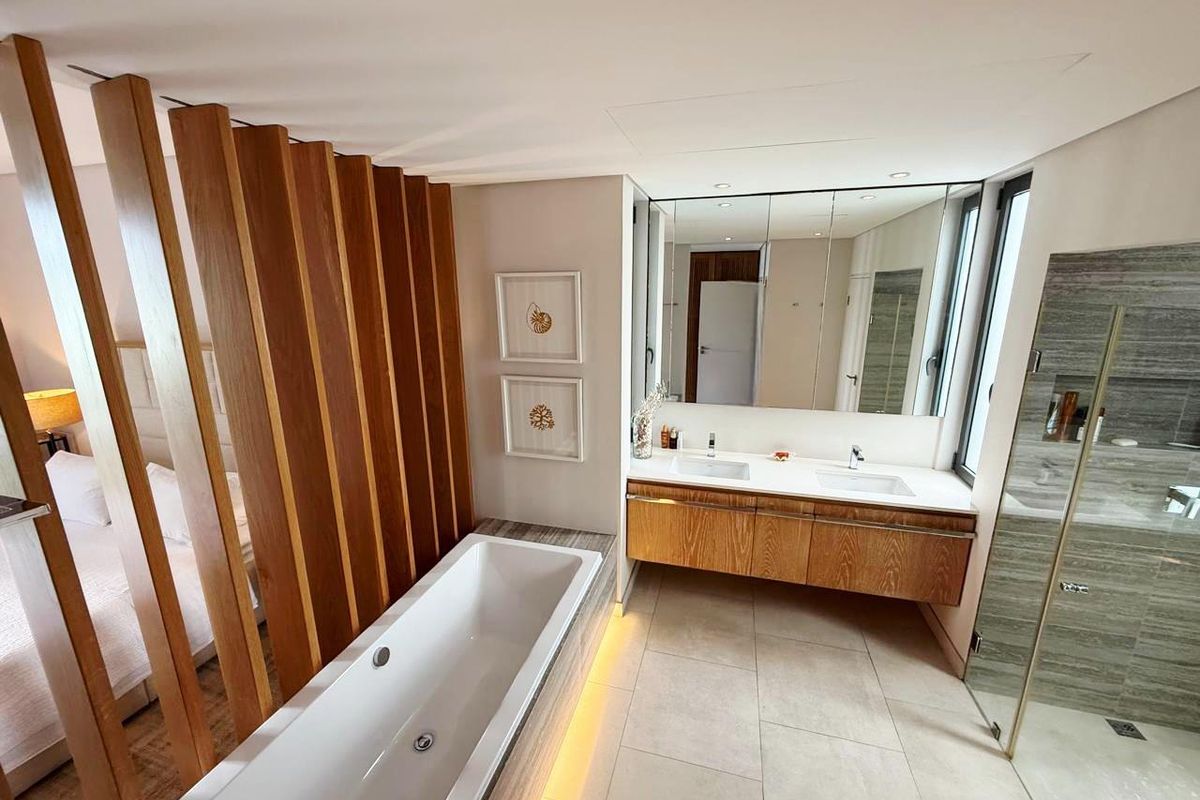 Modern open-plan bathroom featuring a freestanding bathtub, double vanity with timber cabinetry, and a spacious walk-in shower with stone tiling.