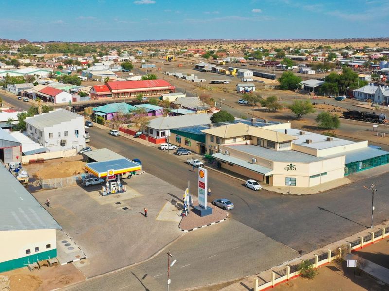 Aerial view of a commercial property featuring a fuel station and adjacent retail building in a town setting.