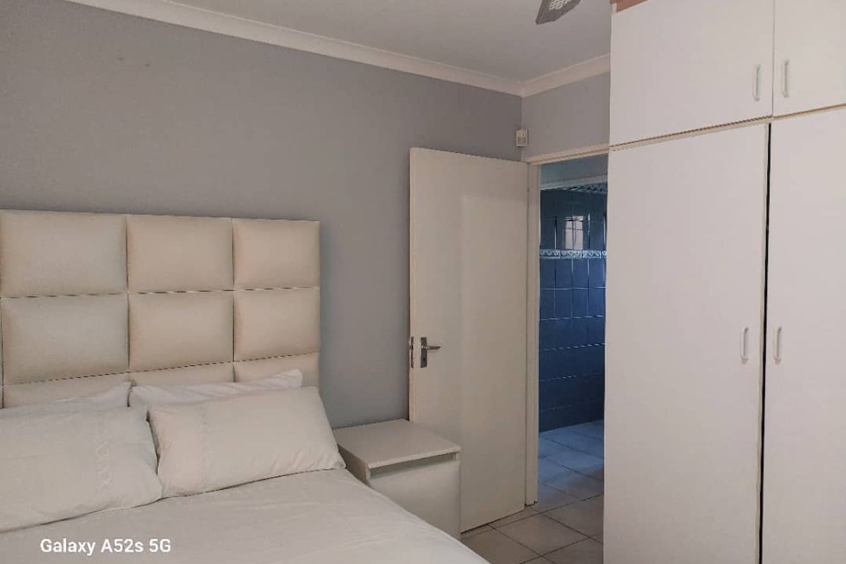 A bedroom featuring built-in cupboards and an adjoining bathroom with tiled flooring.
