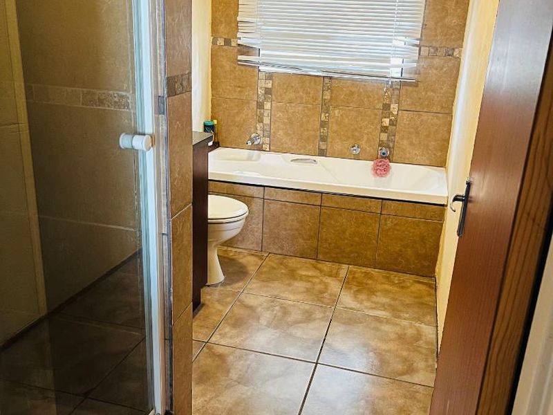 A functional bathroom featuring a built-in bathtub, a separate shower enclosure, and full-height wall tiling.