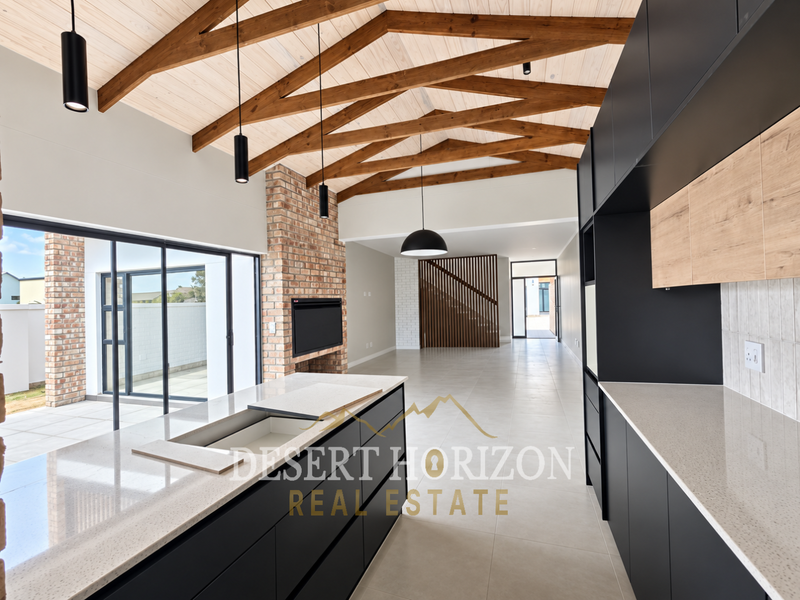 Spacious open-plan living and kitchen area featuring vaulted ceilings with exposed timber trusses, a modern brick fireplace, and sleek contemporary cabinetry.