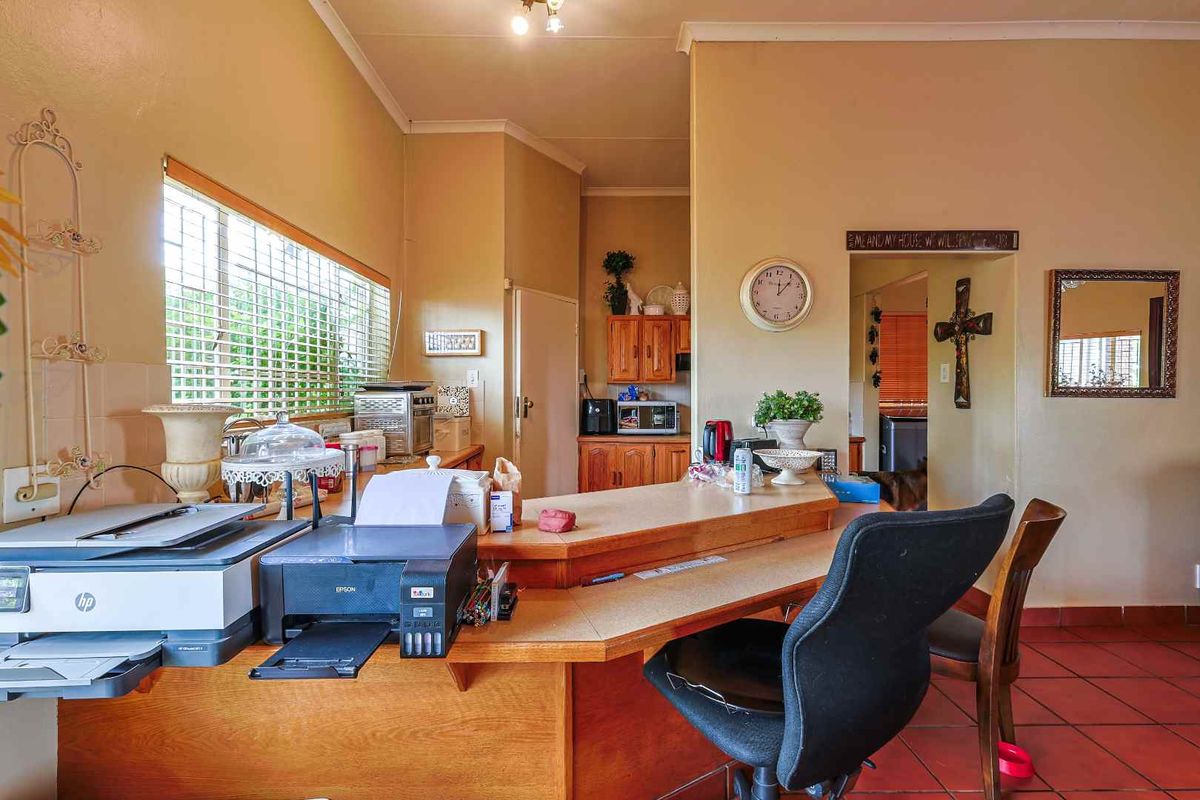 A functional kitchen area featuring a built-in wooden breakfast bar, tiled flooring, and cabinetry, providing a practical workspace within the home.