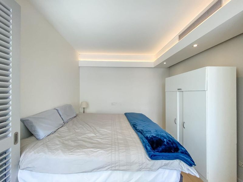 A clean, modern bedroom featuring a built-in wardrobe, recessed ceiling lighting, and integrated ducted air conditioning.