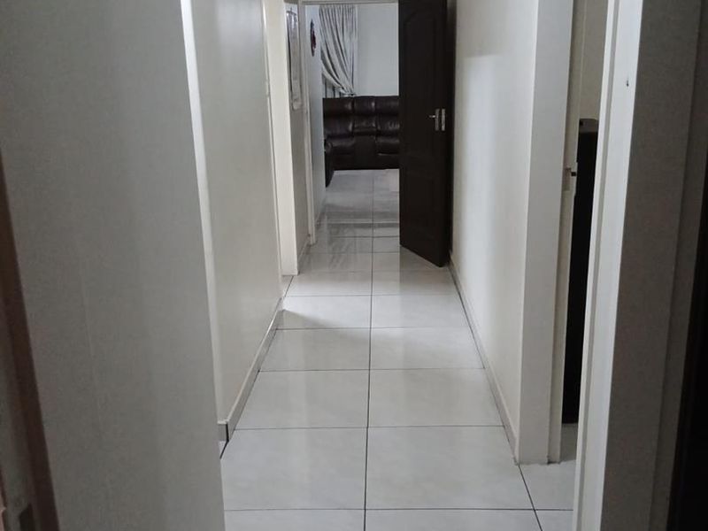 A clean, neutral hallway featuring light-colored floor tiles and multiple internal doorways providing access to adjacent rooms.