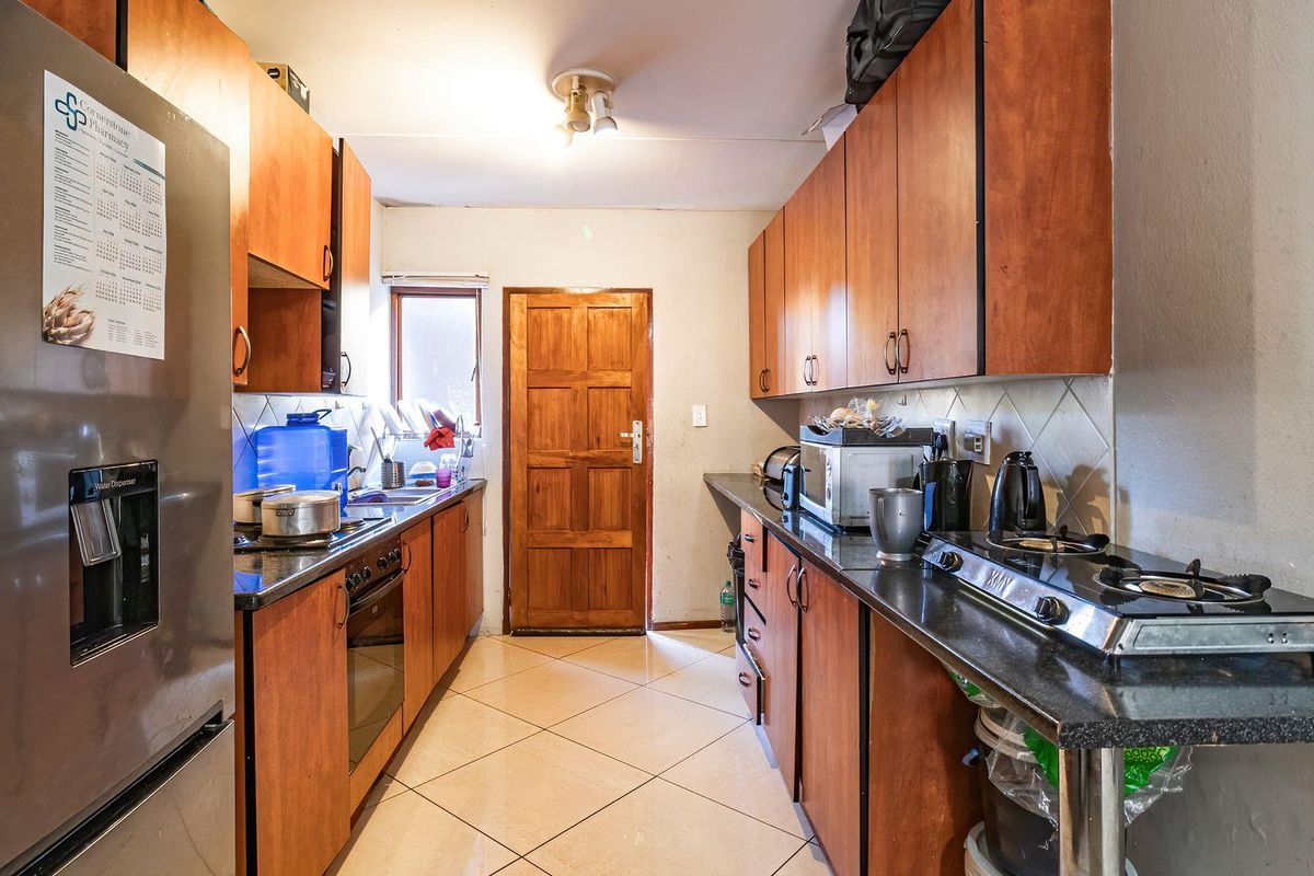 A functional galley-style kitchen featuring wooden cabinetry, granite countertops, a gas hob, and a built-in oven, offering practical workspace and storage.
