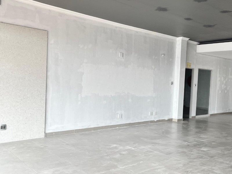 An empty, open-plan retail space featuring tiled flooring and unfinished wall and ceiling surfaces, ready for final fit-out and customization.