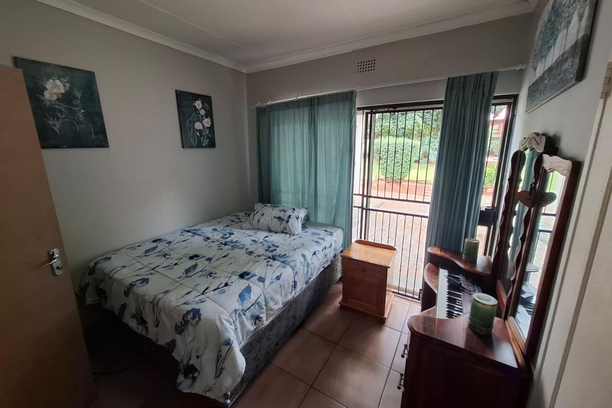 A functional bedroom featuring tiled flooring, built-in storage, and a sliding glass door providing direct access to the exterior.