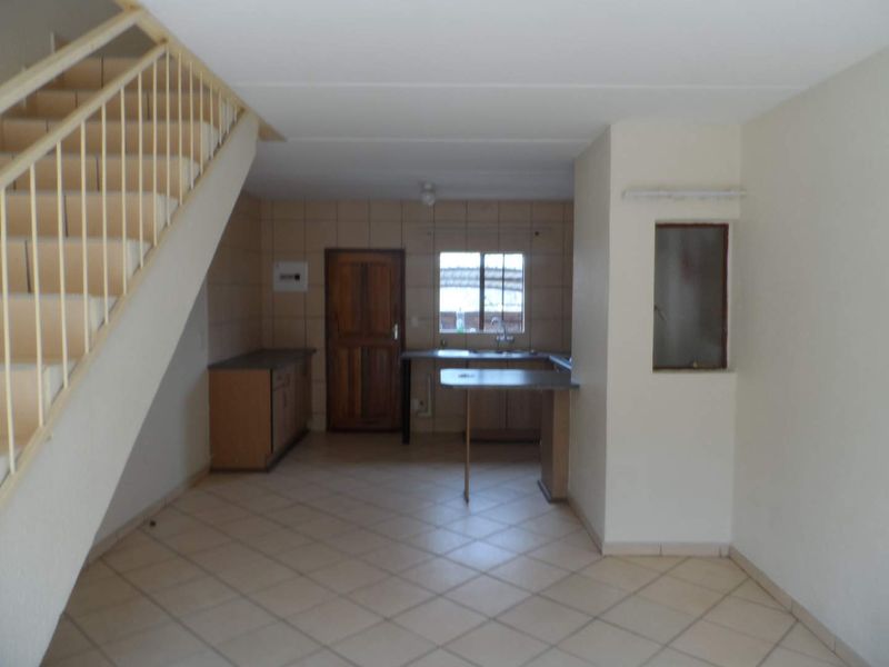 Open plan living area featuring a staircase and a functional kitchen with built-in cabinetry and a breakfast bar.