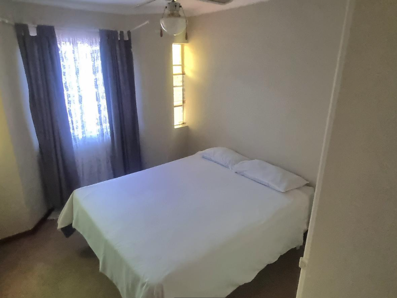 A compact bedroom featuring a ceiling fan and multiple windows providing natural light.