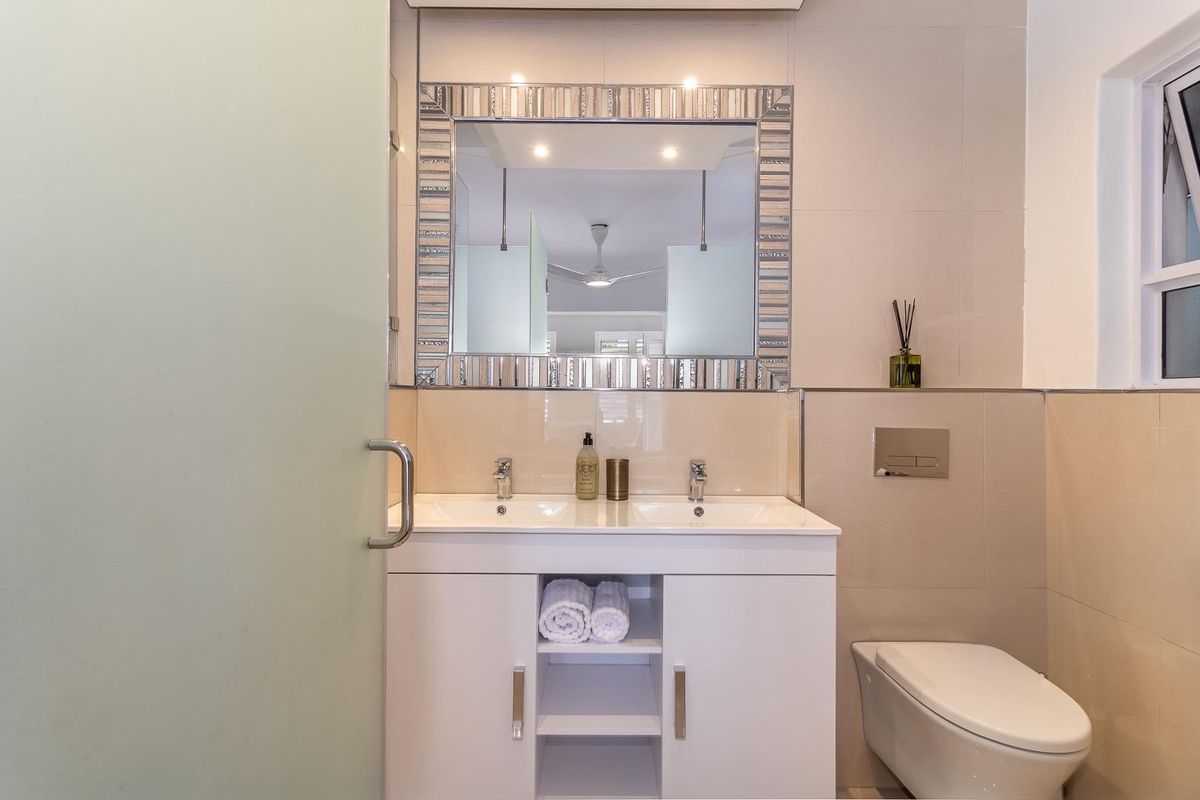 Modern bathroom featuring a double vanity with integrated sinks, wall-mounted toilet, and large decorative mirror.