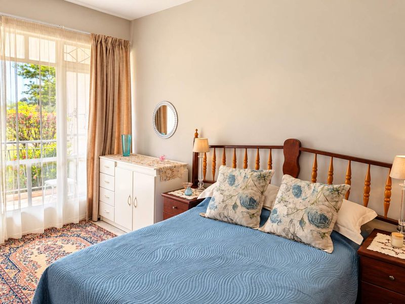 A well-lit bedroom featuring a sliding glass door that provides direct access to a private balcony, allowing for natural light and outdoor views.