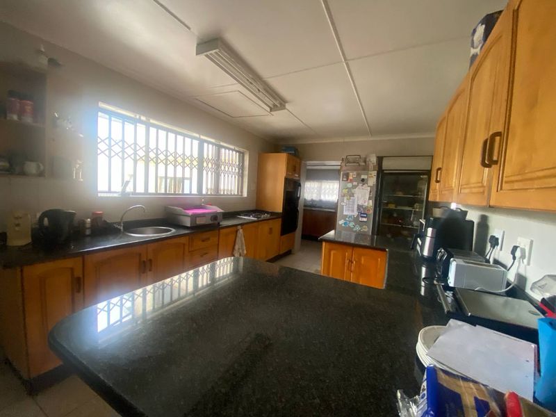 A functional kitchen featuring wooden cabinetry, granite countertops, and a built-in oven, with a window fitted with security bars.