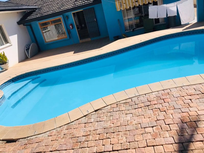 Outdoor pool area featuring a swimming pool with tiled coping and paved patio space, adjacent to the main building structure.