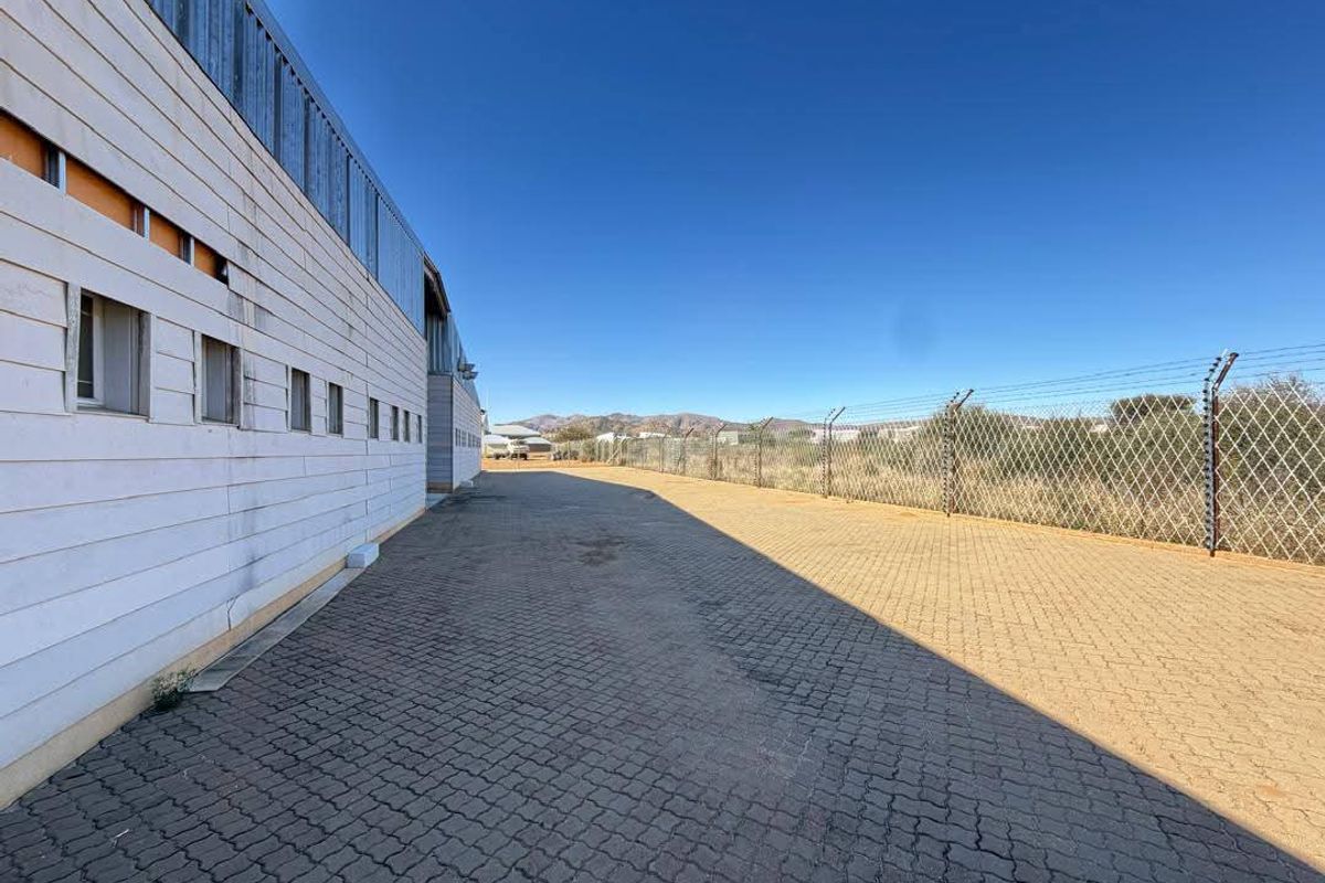 Exterior view of the industrial property featuring paved yard space, perimeter security fencing, and metal cladding facade.