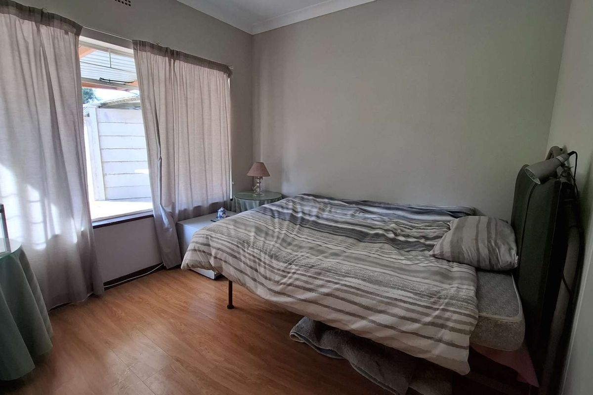 A functional bedroom featuring laminate flooring and a window with natural light, providing a neutral base for personalization.