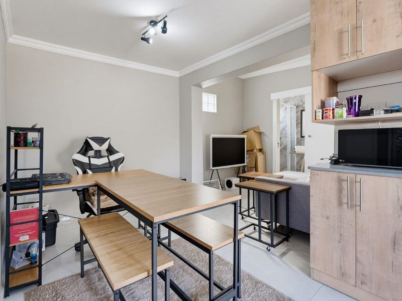 Open plan living area featuring tiled flooring, modern cove cornicing, and built-in cabinetry, providing a versatile space for dining and relaxation.