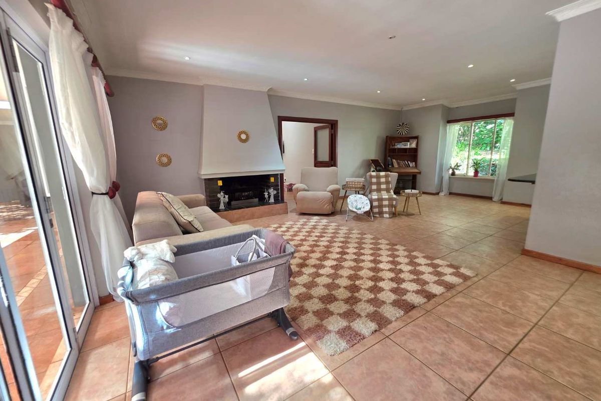 Spacious living room featuring tiled flooring, a central fireplace with a built-in hearth, and large sliding glass doors providing access to the patio.