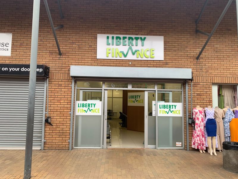 Front facade of a retail unit featuring brickwork, a roller shutter door, and prominent business signage at the entrance.