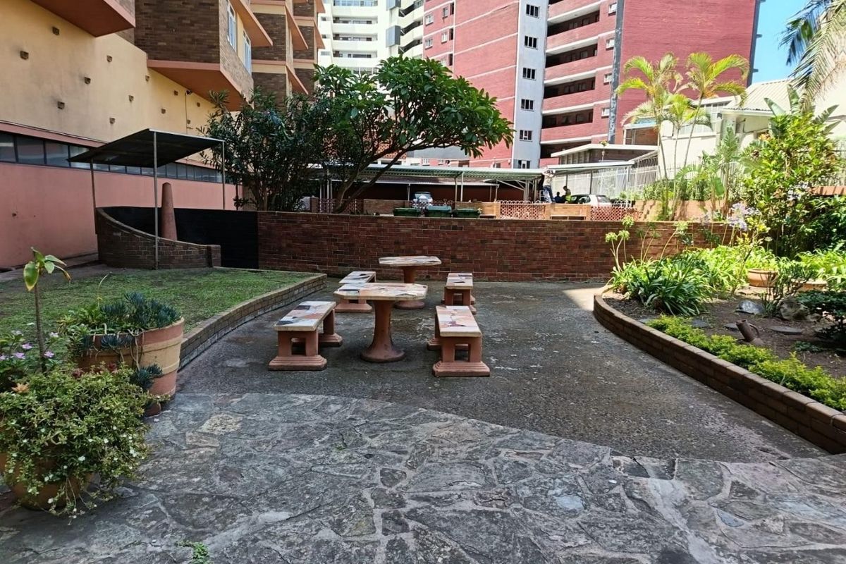 A communal outdoor courtyard area featuring stone paving, a brick retaining wall, and built-in stone seating within an apartment complex setting.