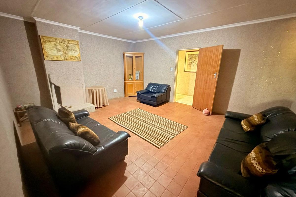A spacious living room featuring tiled flooring, textured walls, and a simple ceiling finish, providing a functional base for renovation.