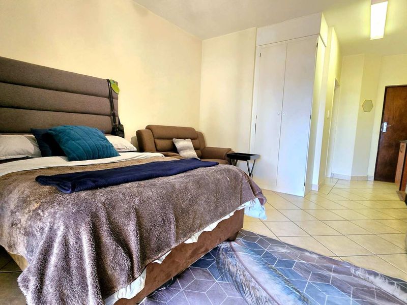 Open-plan studio apartment featuring tiled flooring, built-in wardrobe storage, and a functional layout combining sleeping and living areas.