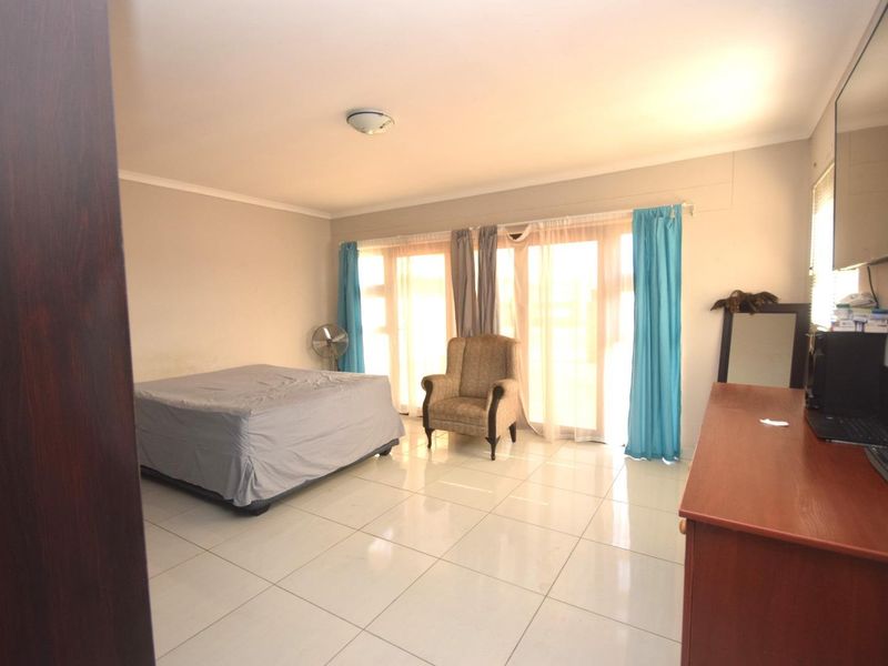 Spacious bedroom featuring large sliding glass doors that provide ample natural light and tiled flooring throughout.
