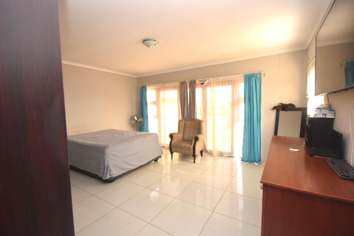 Spacious bedroom featuring large sliding glass doors that provide ample natural light and tiled flooring throughout.