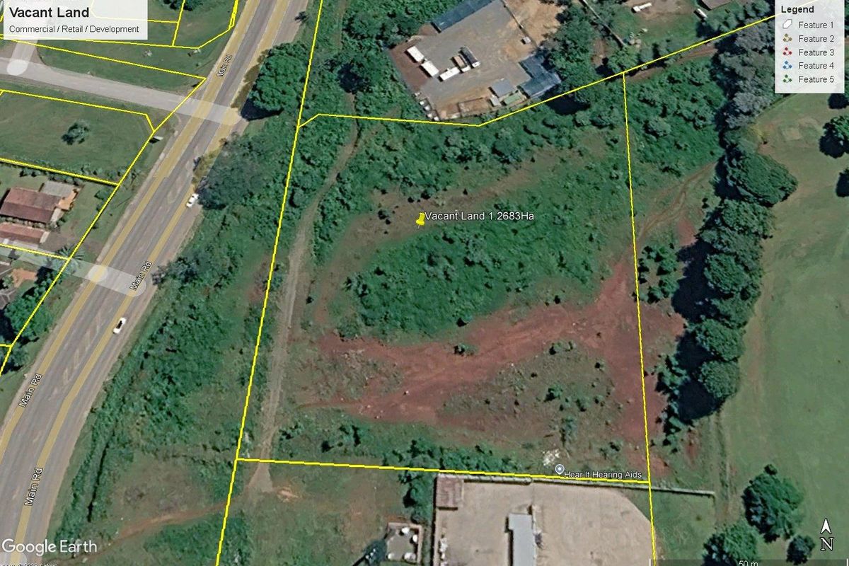 Aerial view of a 1.2683-hectare vacant commercial land parcel with road access and surrounding vegetation.