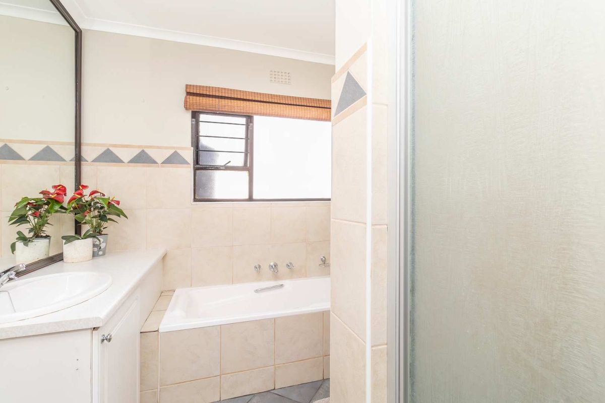 A functional bathroom featuring a built-in bathtub, vanity with integrated basin, and a separate shower enclosure with frosted glass door.