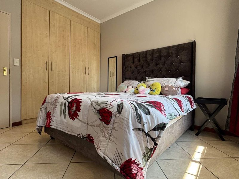 A well-maintained bedroom featuring neutral tiled flooring and ample built-in cupboard storage space.