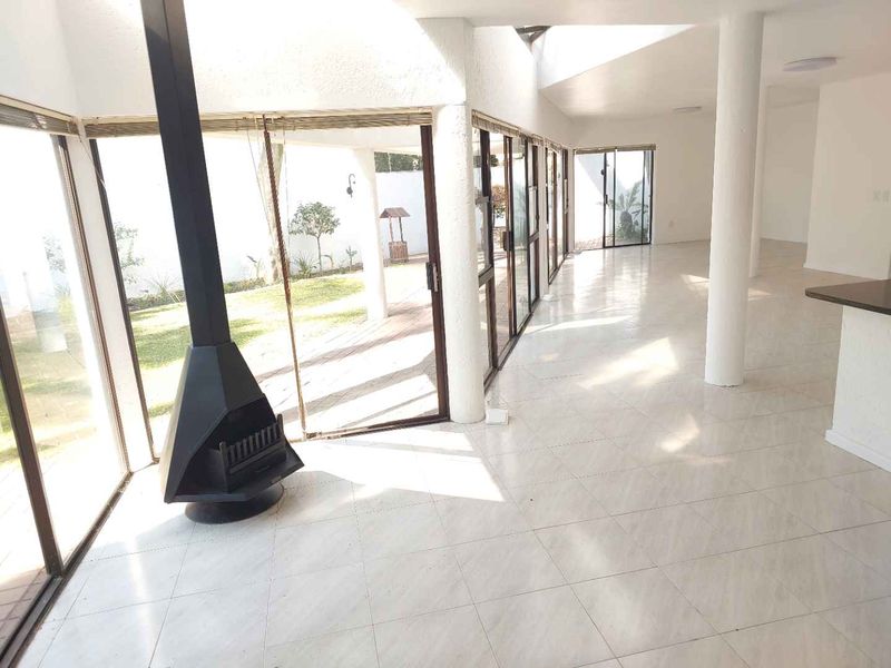 Spacious open-plan living area featuring large sliding glass doors, tiled flooring, and a modern freestanding fireplace with direct garden access.