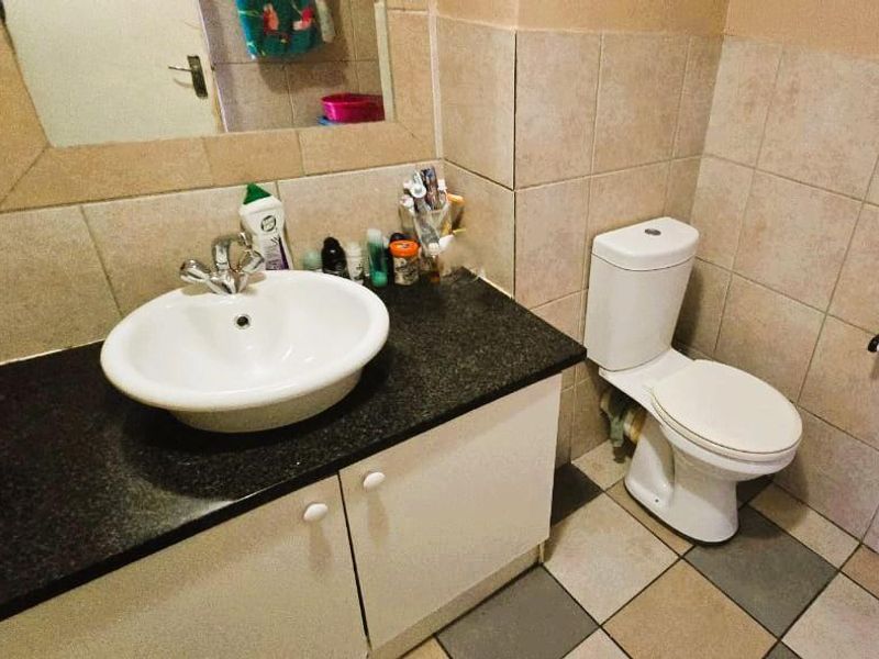 A functional bathroom featuring a vessel sink on a granite vanity, tiled walls, and standard ceramic flooring.