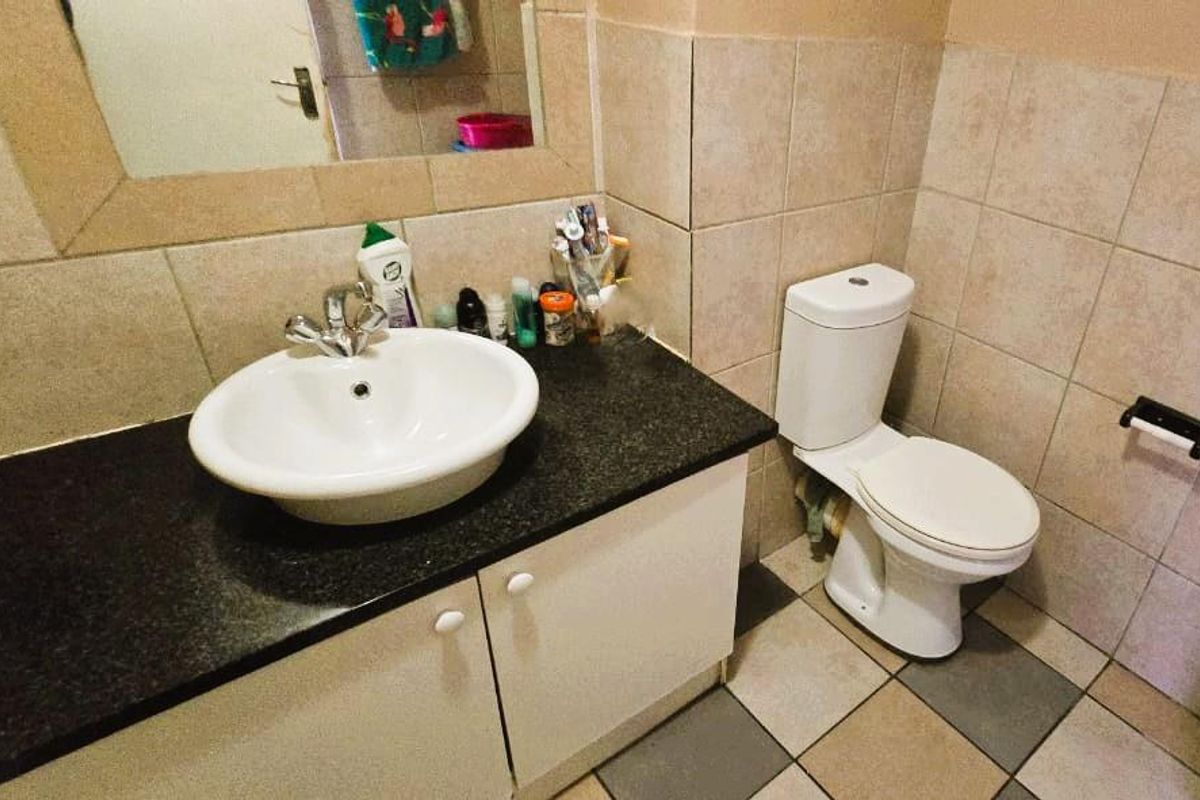 A functional bathroom featuring a vessel sink on a granite vanity, tiled walls, and standard ceramic flooring.