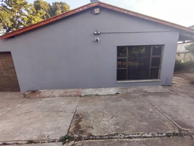 Front exterior view of the property featuring a concrete driveway, garage access, and security cameras mounted on the facade.