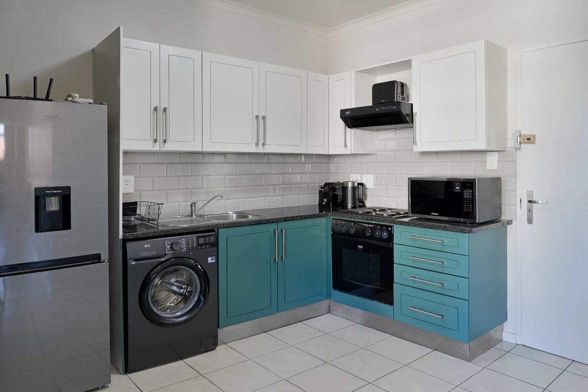 Modern kitchen featuring two-tone cabinetry, subway tile backsplash, stone countertops, and integrated appliances including an oven and extractor fan.