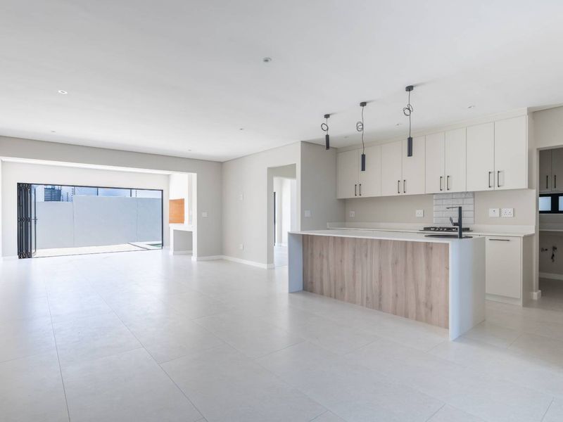 Spacious open-plan living area featuring a modern kitchen with a central island, sleek cabinetry, and seamless flow to the outdoor patio through bi-fold doors.
